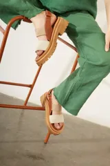 Sandalias de cuero color marrón con plataforma y suela track. Presentan dos tiras anchas, una de cuero liso y otra con textura tipo piel de reptil.