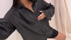 Camisa color beige claro con textura brillante, cuello clásico, cierre frontal con botones y mangas largas con puños abotonados.