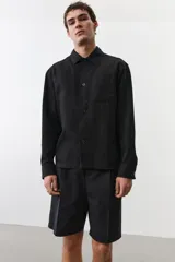 Sobrecamisa negra de manga larga con cuello inglés, tapeta lisa, canesú en la espalda y bolsillo superior de parche.
