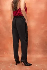 Pantalón de vestir gris con cintura elástica en la parte trasera, corte recto y franja lateral de lentejuelas negras.
