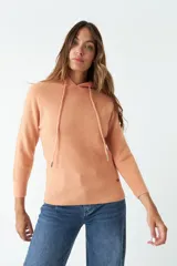 Sweater tejido color salmón con capucha y cordones ajustables.
