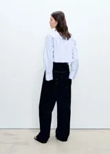 Camisa corta de popelina de algodón a rayas verticales celestes y blancas, con cuello camisero, mangas largas con puños abotonados, bolsillo de parche en el pecho y cierre frontal con botones.