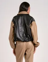 Campera bomber de cuero sintético negra con mangas color beige, cuello clásico y cierre frontal con cremallera.
