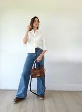 Cartera bandolera de cuero color marrón tostado, con doble asa corta y correa larga desmontable. Tiene un bolsillo frontal con cierre y un bolsillo interno.