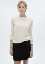 Buzo de punto fino color crema, con cuello redondo y mangas largas.