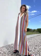 Vestido largo de tejido con diseño geométrico en tonos celeste, marrón, rojo y blanco. Tiene escote en V y aberturas laterales.