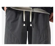 Pantalón cargo negro de corte ancho, confeccionado en gabardina de algodón. Presenta cintura elástica y regulable con cordón blanco, y múltiples bolsillos cargo laterales con costuras destacadas.