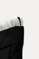 Pantalón ancho gris con textura de espiga, tiro alto, doble cintura elástica ajustable con cordón, pinzas frontales, bolsillos delanteros y falso bolsillo de vivo en la espalda.