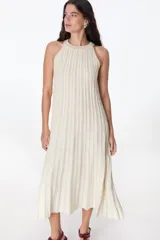 Vestido largo de tejido de punto, color celeste con rayas verticales en azul oscuro y brillo sutil por el lurex. Diseño sin mangas con cuello halter y silueta en A.