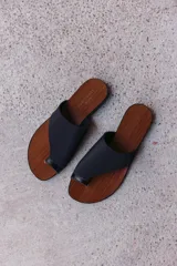 Sandalias planas color beige con base marrón, tira ancha de tela y tira fina entre los dedos.