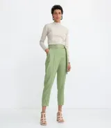 Pantalón zanahoria color verde claro, de tiro alto, con cinturón de la misma tela y hebilla doble.