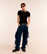 Pantalón de jean super baggy azul oscuro, con trabillas en la cintura, bolsillos laterales tipo cargo con cordones ajustables y cierre frontal con cremallera y botón.