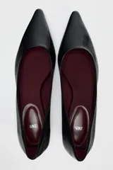 Zapato plano de charol negro con punta fina y suela baja.