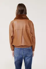 Campera bomber de cuero color marrón con cierre frontal, cuello clásico, bolsillos plaqué con tapa y puños y cintura acanalados.