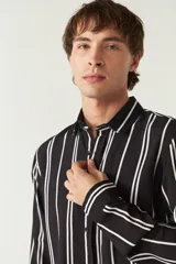 Camisa de mangas largas con estampado a rayas verticales en tonos verde oliva, blanco y azul. Corte regular y logo bordado en el pecho. Confeccionada en viscosa.
