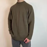 Sweater verde oliva de tejido grueso con cuello alto.