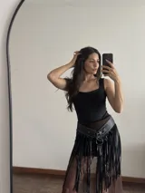 Cinto tipo falda de cuero sintético negro con flecos largos y tachas plateadas.
