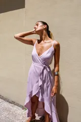 Vestido largo blanco de crepé con escote en V, breteles finos y corte envolvente con volados en el ruedo.