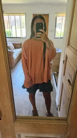 Buzo de tejido liso, color terracota/naranja quemado, de corte muy holgado y mangas largas.