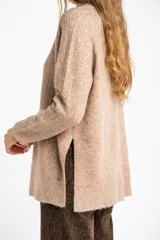 Sweater color beige de tejido texturado, con cuello redondo y mangas largas.