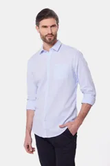 Camisa de lino color beige, de manga larga, con cuello clásico y bolsillo en el pecho.