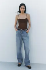 Pantalón de jean celeste de tiro alto, corte recto y largo hasta el tobillo. Tiene cinco bolsillos, trabillas en la cintura, efecto lavado y cierre frontal con cremallera y botón.