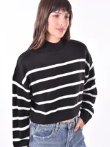 Polerón de tejido de punto color verde militar, con cuello alto acanalado y diseño de rayas horizontales blancas. Presenta un corte corto y mangas largas.