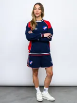 Buzo de felpa azul marino con mangas raglán rojas y detalles tricolor en puños, mangas y cuello. Incluye logo de Umbro bordado en el pecho y escudo del Club Nacional de Football.