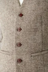 Chaleco de vestir para hombre, color marrón claro con textura tweed. Diseño sastrero con cuello en V, cierre frontal con botones, bolsillos ribeteados y forro interno. Confeccionado en lana fina sin teñir, diseñado exclusivamente por Don Baez.