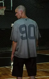 Remera de manga corta, cuello redondo y calce oversize, color gris oscuro con efecto batik/lavado. Estampado frontal con la palabra "Ravers" en tipografía cursiva estilo universitario en tono azul oscuro.