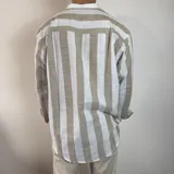 Camisa celeste y blanca a rayas verticales, de lino, con cuello mao y mangas largas con puños.