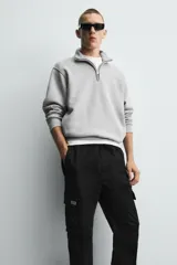 Pantalón cargo negro de corte slim fit, confeccionado en tejido de algodón con cintura elástica ajustable con cordón. Cuenta con bolsillos frontales, traseros y bolsillos tipo parche con solapa en los laterales.