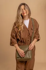 Bandolera de hombro color gris claro, con solapa frontal y correa ajustable. Presenta un diseño simple y práctico, ideal para uso diario.