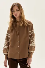 Camisa de calce holgado color marrón camel, confeccionada en Lyocell, con bordados blancos de estilo folclórico en las mangas.