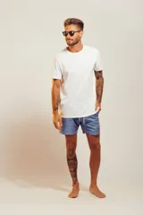 Bañador de hombre color rosa pálido con estampado de golondrinas oscuras. Presenta cintura elástica con cordón ajustable de color crudo y terminales turquesa.