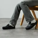 Sandalia tipo zueco (clog) Birkenstock modelo Boston, fabricada en EVA, color negro. Presenta una tira ajustable con hebilla metálica sobre el empeine.