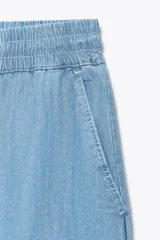 Pantalón celeste de tiro alto con cintura elástica ajustable con cordones, bolsillos delanteros y traseros, y pernera ancha.