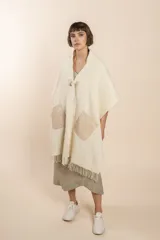 Chal de lana fina sin teñir, con calce en hombros, abrochadura con alamar de fieltro, bolsillos de cuero y terminación con flecos. Diseño exclusivo de Don Baez, hecho en Uruguay.