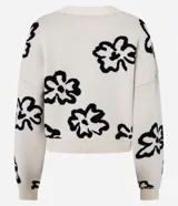 Cardigan color crema con estampado de flores abstractas en negro, escote en V, cierre frontal con botones y mangas largas.