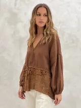 Blusa marrón de lino con escote en V, mangas largas abullonadas y detalle de encaje en la parte inferior.