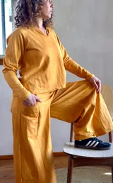 Conjunto de buzo liviano con cuello en V y bolsillo en el pecho, y pantalón palazzo evasé color mostaza batik.