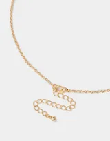 Cadena dorada con dije de moño con apliques de perlas.