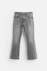 Pantalón de jean negro con efecto lavado, corte flare, cinco bolsillos, cierre frontal con cremallera y botón, y bajo con acabado irregular.