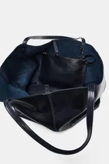 Bolso tipo maxi shopper de piel, color azul marino oscuro, con asas de hombro y pespuntes a tono. Presenta un cierre mediante tiras con botón y un bolsillo interior extraíble.