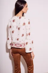 Blusa blanca con estampado de cachemir en color marrón y bordado floral en el ruedo y mangas acampanadas.