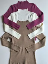 Polera fucsia de tejido de punto con cuello alto y mangas largas con botones decorativos en los puños.