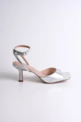 Sandalia plateada de fiesta con diseño elegante y minimalista. Presenta punta cuadrada, tira delantera ancha y pulsera al tobillo con hebilla regulable, que brinda firmeza y comodidad.