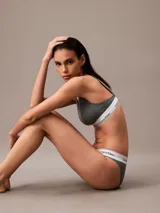 Conjunto de ropa interior Calvin Klein, modelo Modern Cotton, color gris, compuesto por un corpiño triangular con breteles finos regulables y una bombacha tipo tanga. Ambos con banda elástica blanca con logo de la marca.