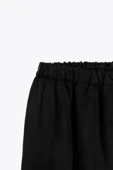 Falda midi negra de tiro alto con cintura elástica y frunces. Presenta detalle de tejido combinado y abertura en la parte trasera del ruedo.