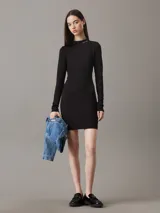 Vestido corto negro de punto milano con cuello perkins, mangas largas y corte ajustado. Logo de Calvin Klein bordado en el cuello.